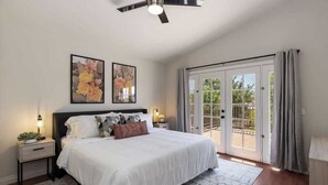 A bedroom with a large bed, two bedside tables, a ceiling fan, and a sliding glass door to an outdoor area. - Indio Escape by Avantstay Stunning Home in Coachella w/ Pool & Hot Tub (Indio)