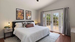 A bedroom with a large bed, two nightstands, a ceiling fan, and a sliding glass door leading to a balcony. - Indio Escape by Avantstay Stunning Home in Coachella w/ Pool & Hot Tub (Indio)