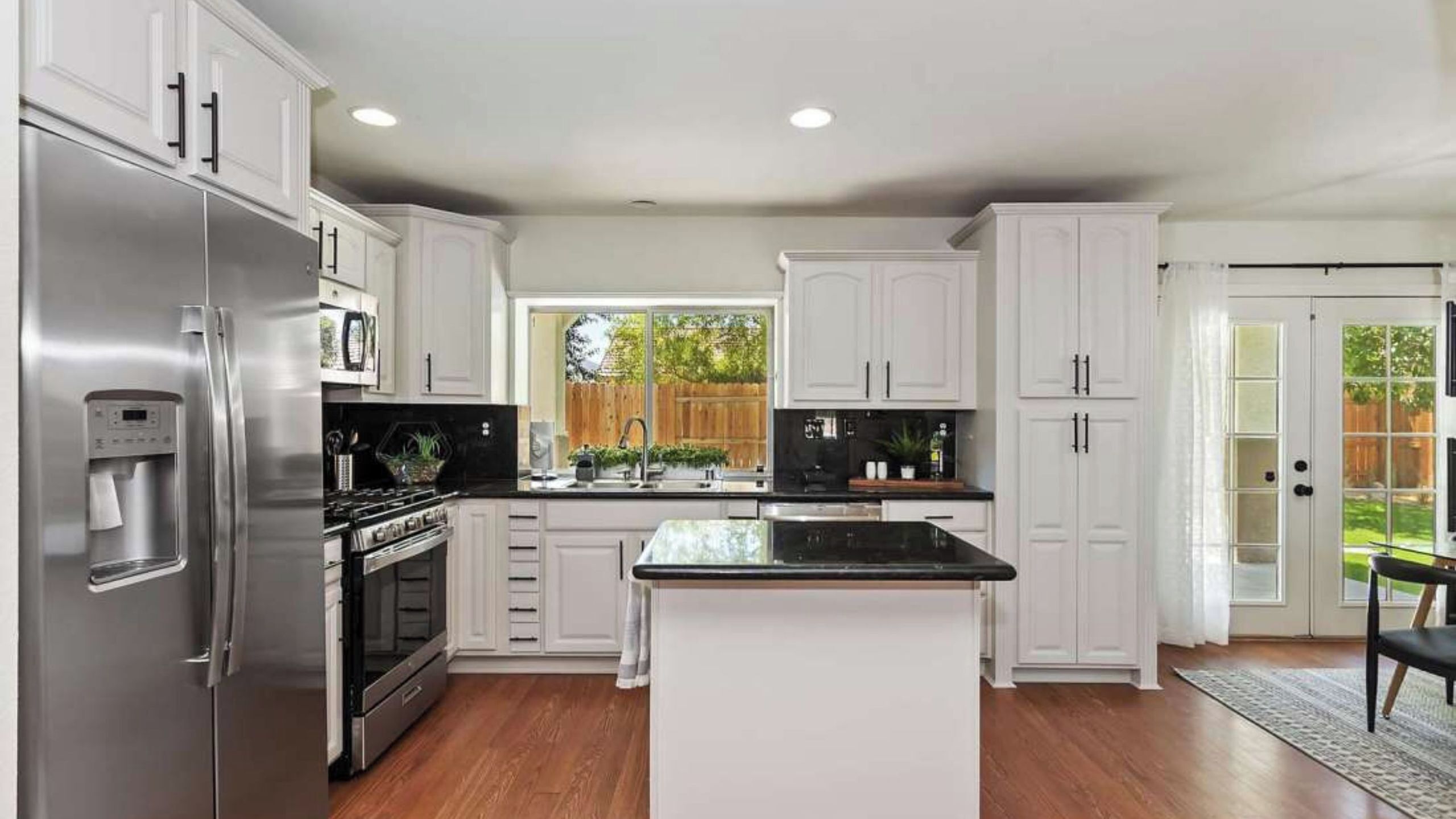 A modern kitchen with white cabinetry, stainless steel appliances, and a central island.