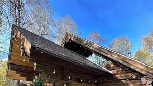 A log cabin with a wooden deck, a small outdoor pool, and a covered patio area.