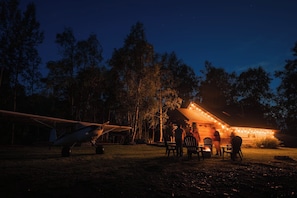A rustic cabin with a dining area and a parked airplane.
