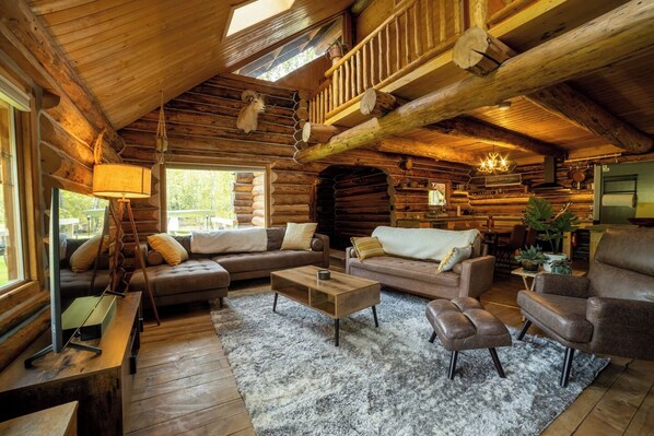 A log cabin interior with a wooden floor, a sofa set, a coffee table, and a fireplace.