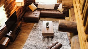 A cozy log cabin interior with a sofa, ottoman, and a coffee table.