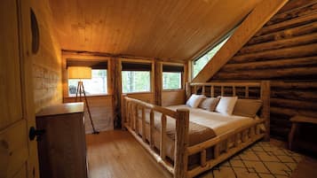 Un dormitorio tipo cabaña de troncos con una cama de madera, un escritorio y una ventana.