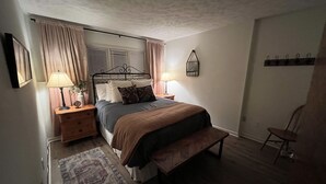 A bedroom with a bed, bedside tables, a bench, a rug, and a chair. - Wintergreen 1bed Condo, Walk to slopes, close to Hiking, Breweries, Wineries (Wintergreen Resort)