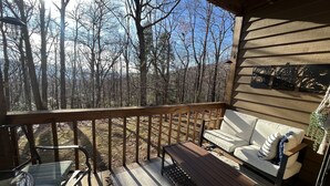 A wooden deck with a bench and a sofa overlooking a forest. - Wintergreen 1bed Condo, Walk to slopes, close to Hiking, Breweries, Wineries (Wintergreen Resort)