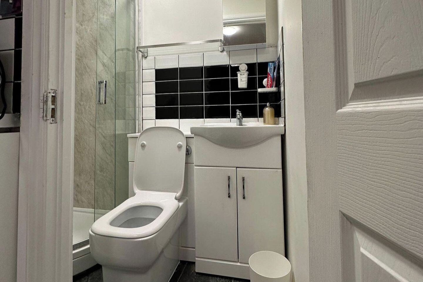A bathroom with a toilet, a sink, and a shower area.