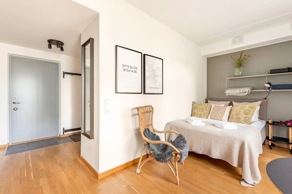 A modern bedroom with a bed, a chair, and two framed pictures on the wall.