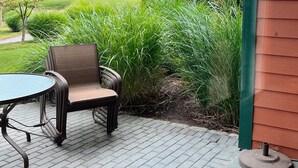 Eine Terrasse mit Tisch und Stühlen, mit Blick auf einen angelegten Garten und eine entfernte Hügelkette.