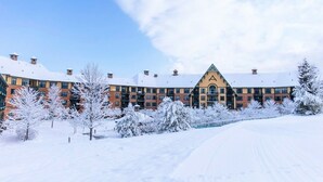 Ein mehrstöckiges Hotel mit einer symmetrischen Fassade, schneebedeckten Bäumen und blauem Himmel.