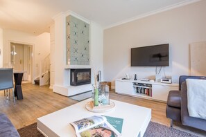 Ein modernes Wohnzimmer mit Kamin, Flachbildfernseher, Couchtisch mit einer Zeitschrift und einer Couch.