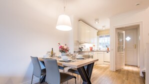 A modern kitchen with white cabinets, a wooden dining table, and a pendant light. - House Ameland, App. 3 - Modern 3-room apartment with approx. 85m² living space, (Wenningstedt-Braderup (Sylt))