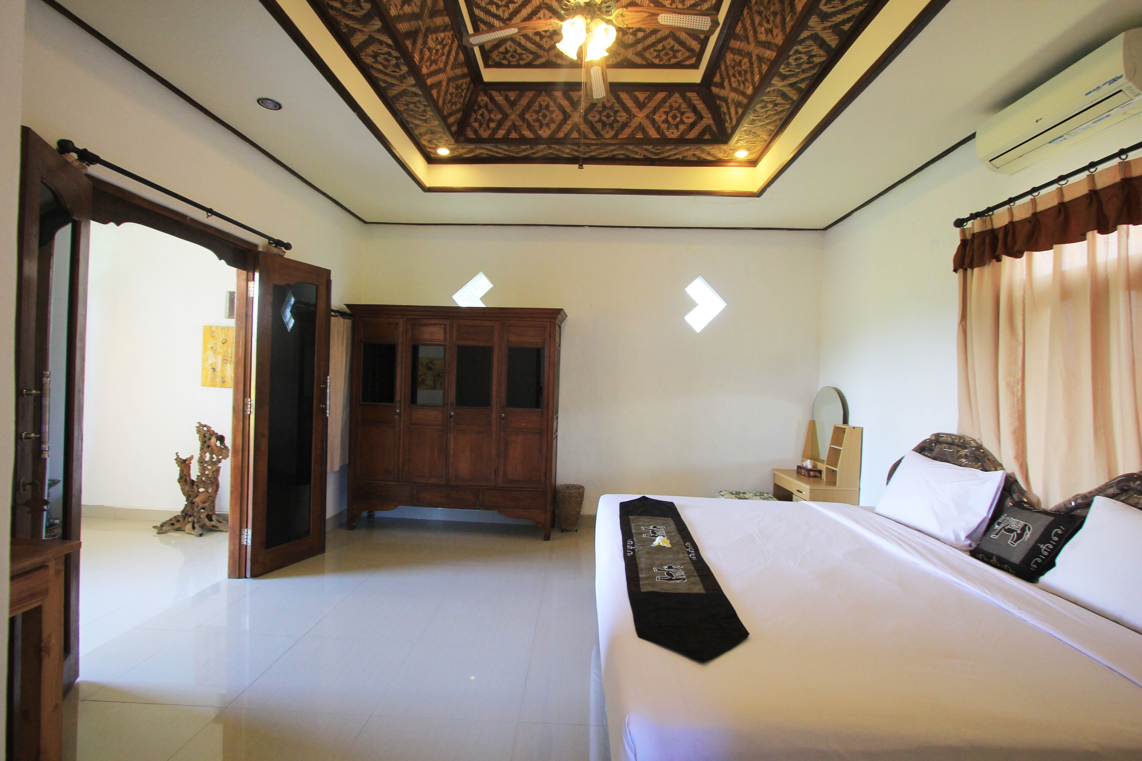A hotel room with a bed, a wardrobe, a ceiling fan, and a nightstand.