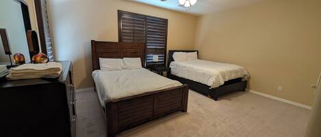 A bedroom with two beds, a ceiling fan, and a dresser.