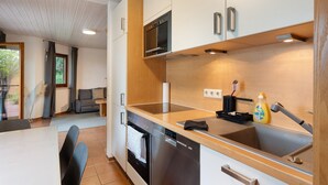 A modern kitchen with a dishwasher, oven, and a wooden countertop. - Haus Ersfeld – Garden Apartment with Private Terrace, Shared Garden, and Wi-Fi (Bad Teinach-Zavelstein)