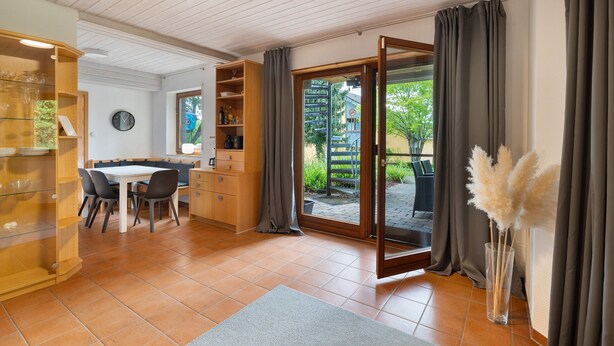 A modern kitchen with a dining area, a large sliding glass door to a patio, and a vase with pampas grass. - Haus Ersfeld – Garden Apartment with Private Terrace, Shared Garden, and Wi-Fi (Bad Teinach-Zavelstein)