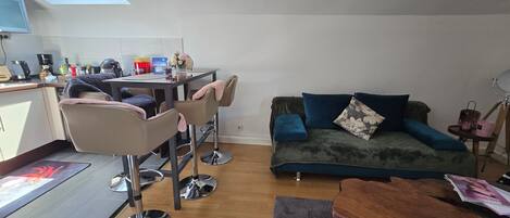 Ein kompakter Wohnbereich mit Küchenzeile, einer Couch, einem Couchtisch und einem Essbereich.