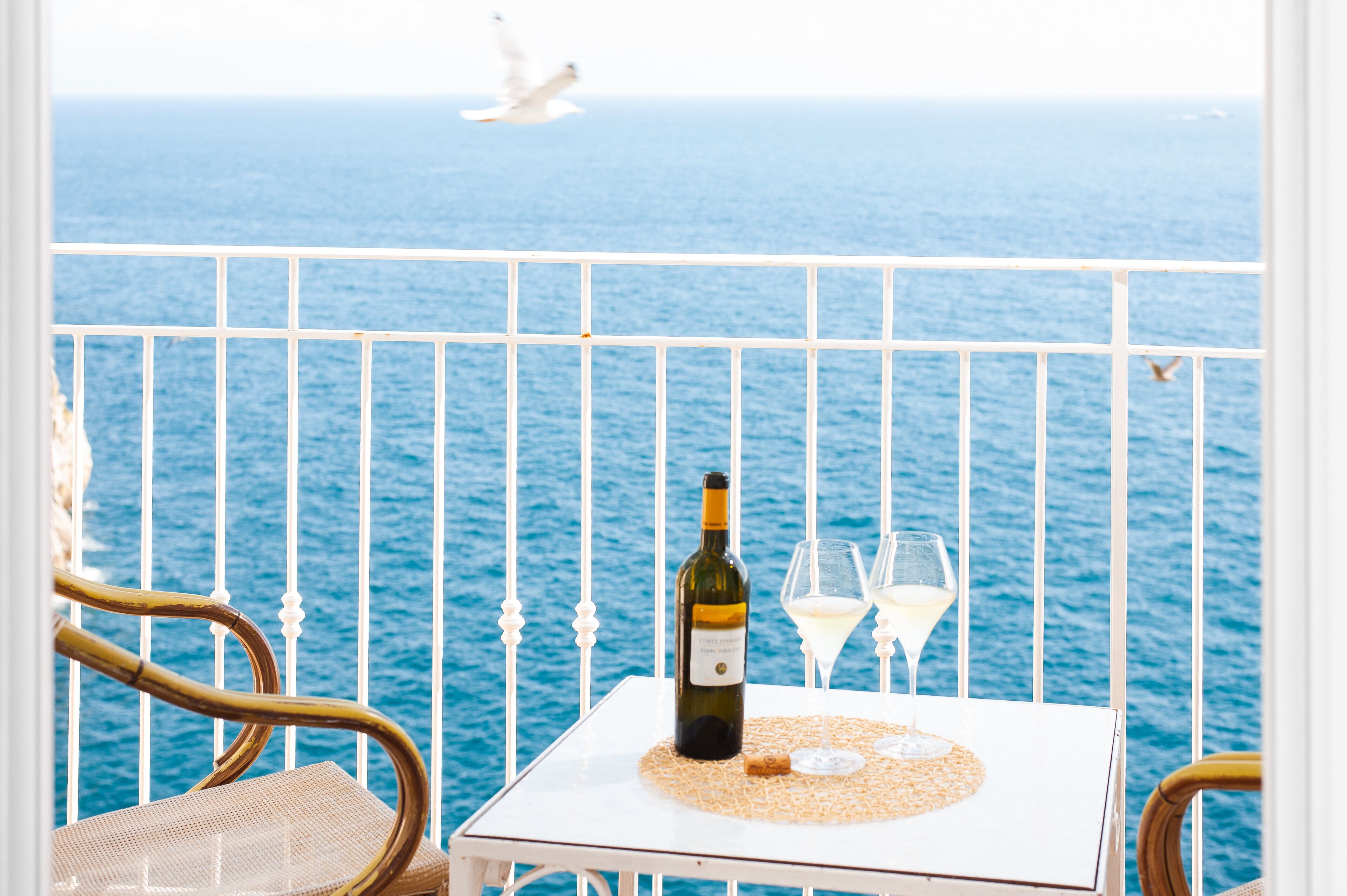Ein Balkon mit Tisch, einer Weinflasche und zwei Gläsern.