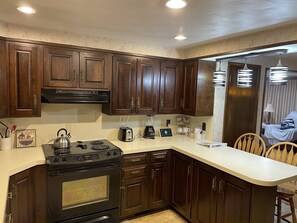 A kitchen with dark wooden cabinets, a black stove, a toaster, and a blender.