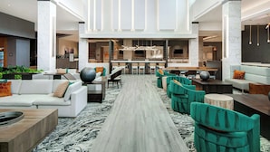 A spacious lobby with a central walkway, seating areas, and a reception desk. - Embassy Suites By Hilton Alpharetta Halcyon (Alpharetta)