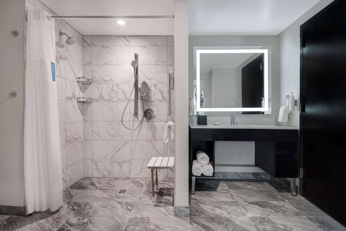 A modern bathroom with a shower, a vanity with a mirror, and a towel rack.