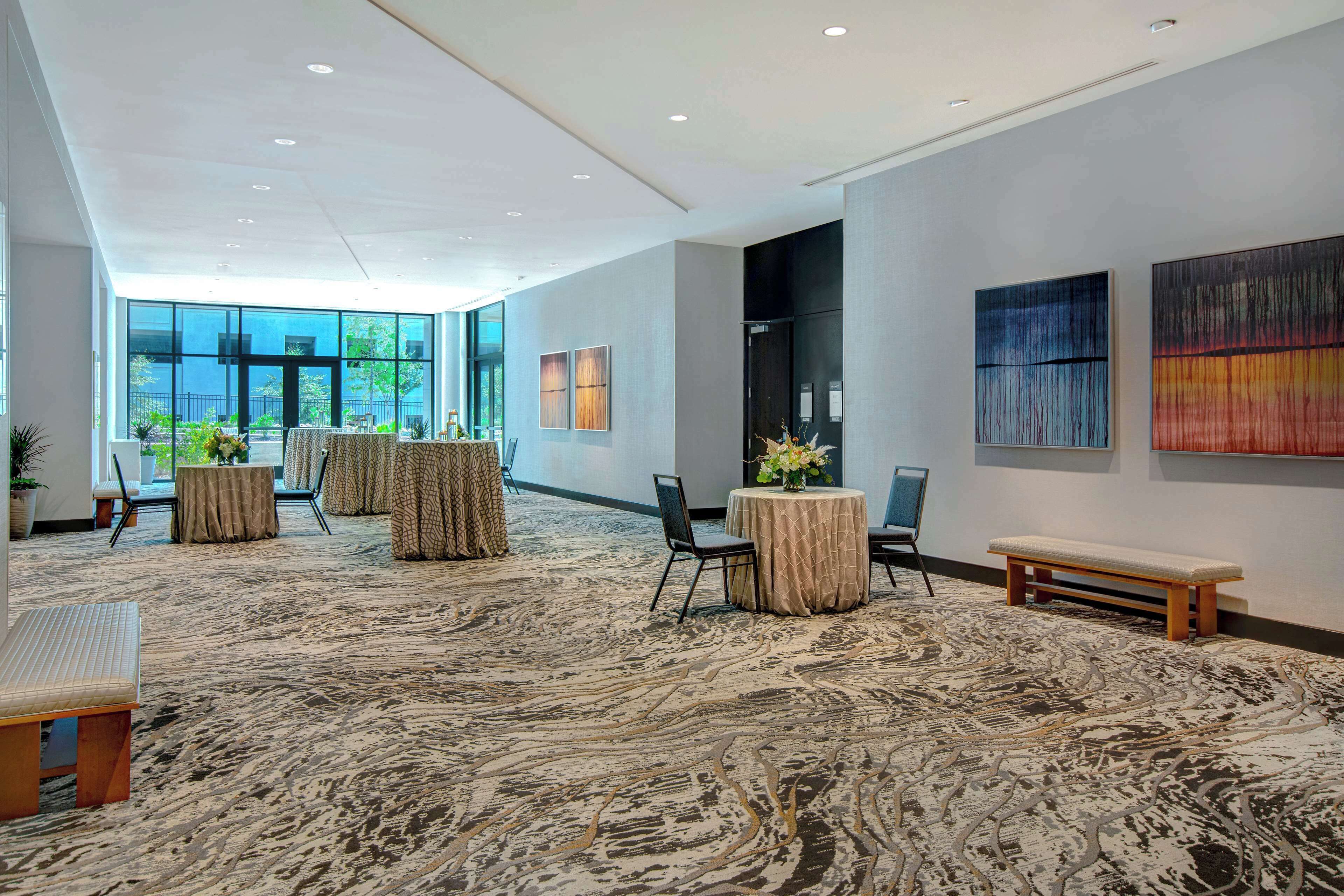 A spacious lobby with a patterned carpet, seating areas, and large windows offering a view of the outdoors.