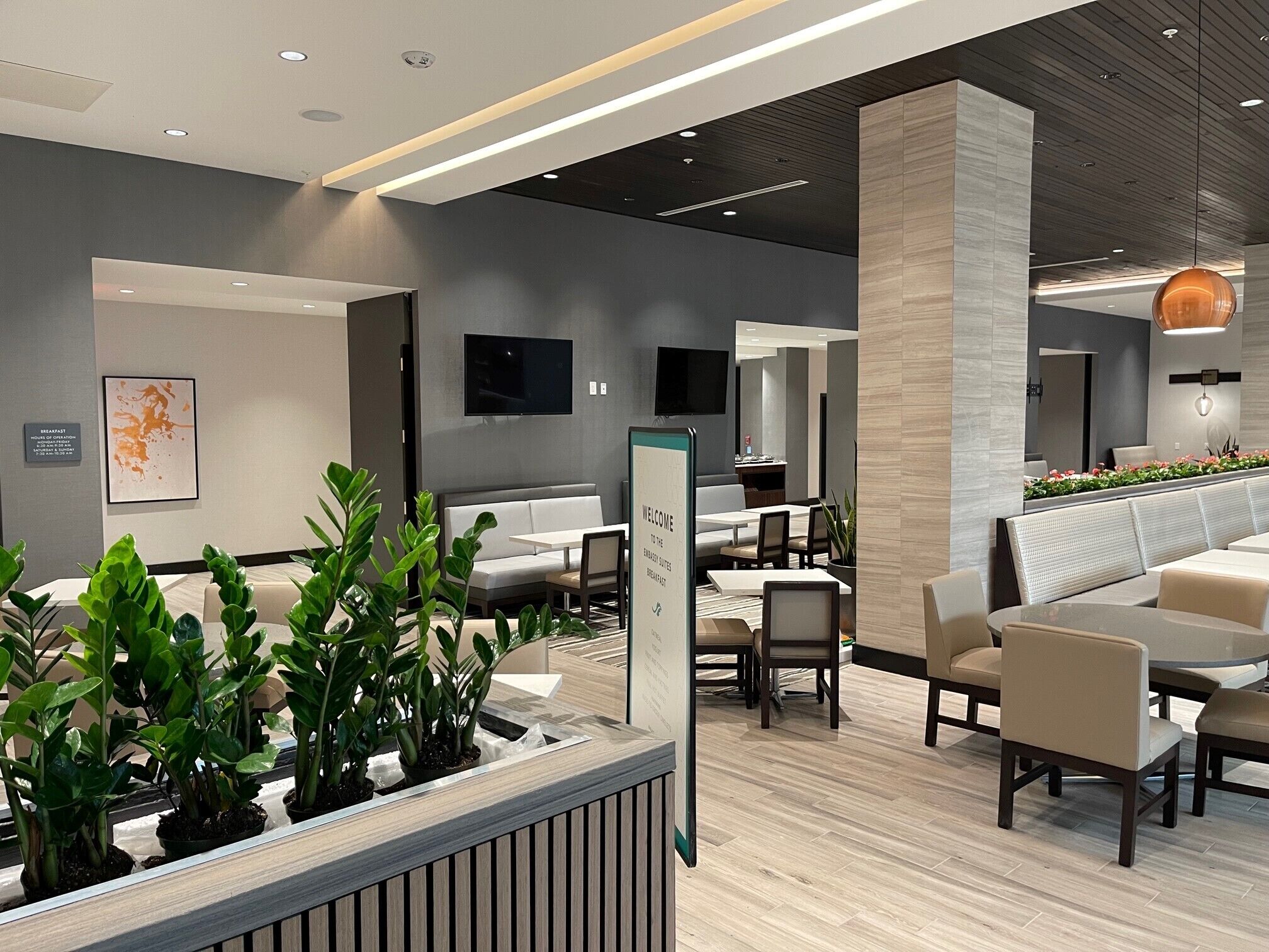 A modern interior with seating areas, a reception desk, and a television on the wall.
