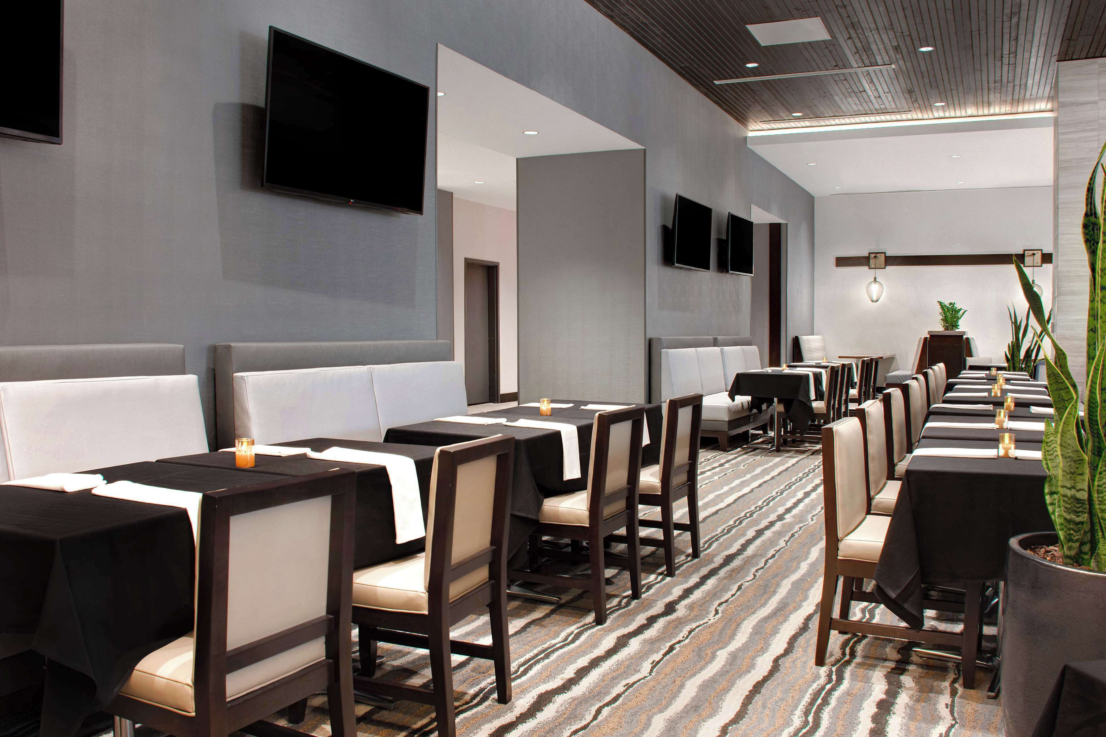 A hotel dining area with long tables, chairs, and a patterned carpet.
