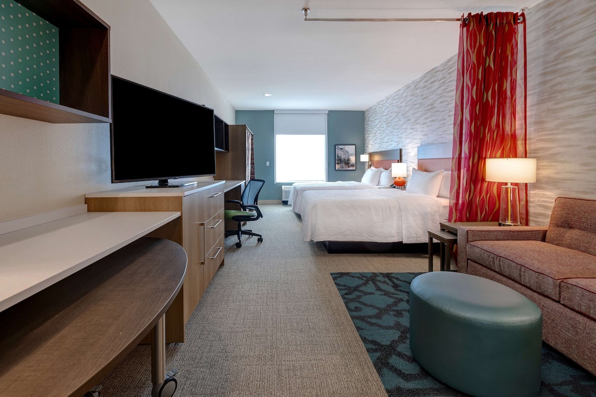 Een hotelkamer met een bed, een bureau met televisie, een stoel, een bank en een lamp.