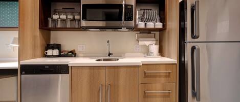 A compact kitchen with a dishwasher, a microwave, a refrigerator, and a coffee maker.