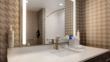 A modern bathroom with a large mirror, a sink, and a shower.