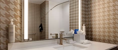 Un baño moderno con un espejo grande, un lavamanos y una ducha.