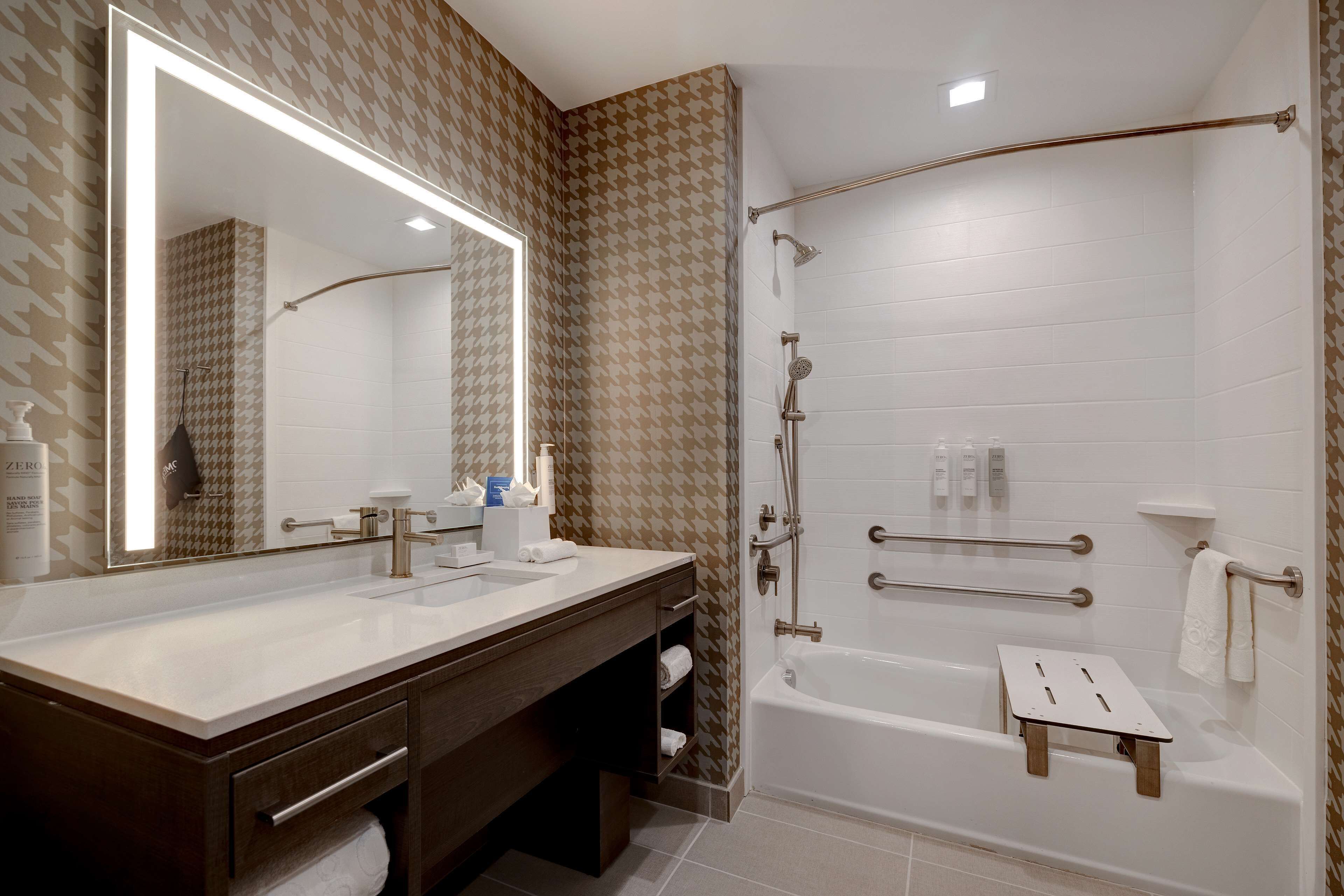 Une salle de bain moderne avec un grand miroir, une baignoire et un espace douche.