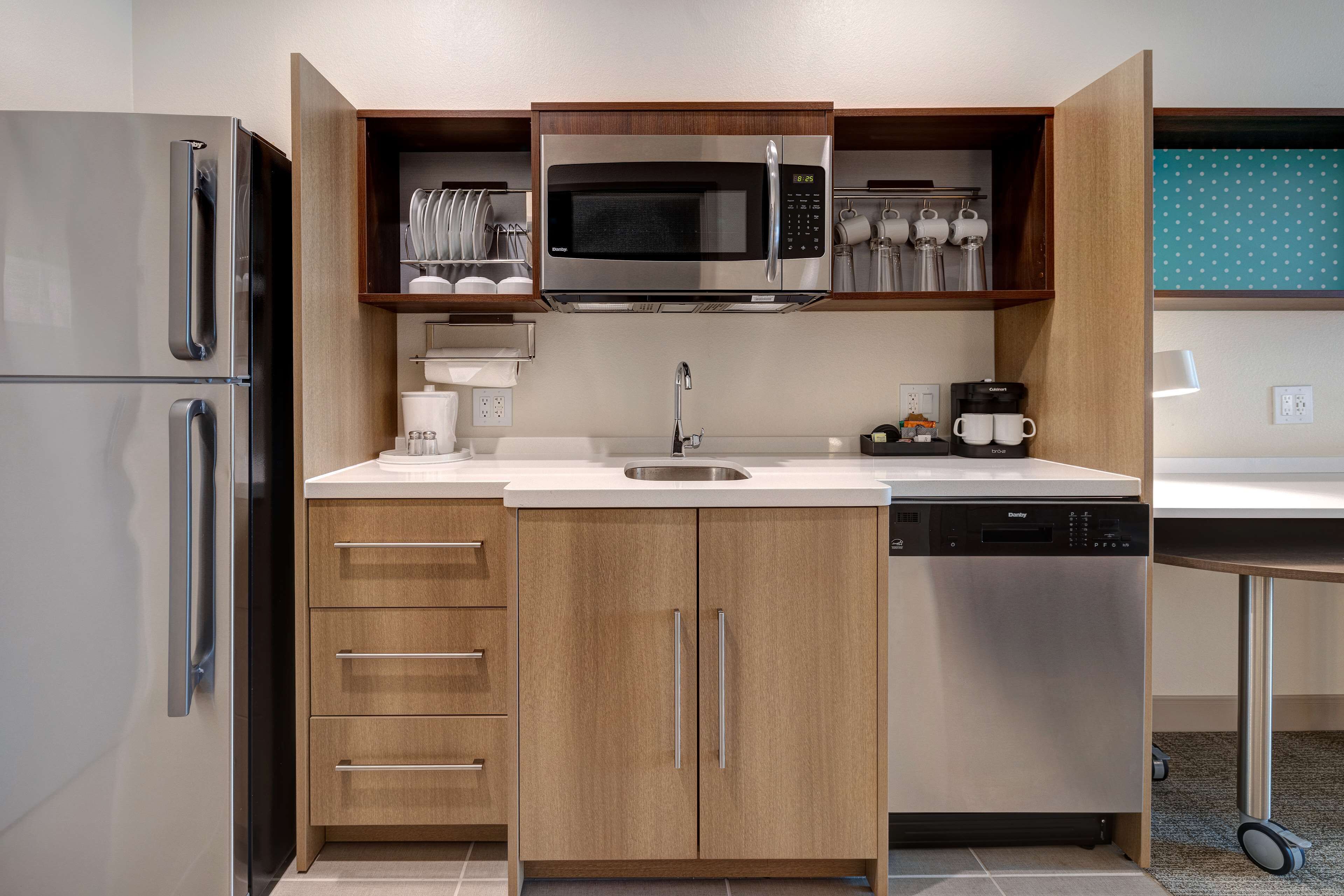 Una cocina compacta con microondas integrado, cafetera y lavavajillas.