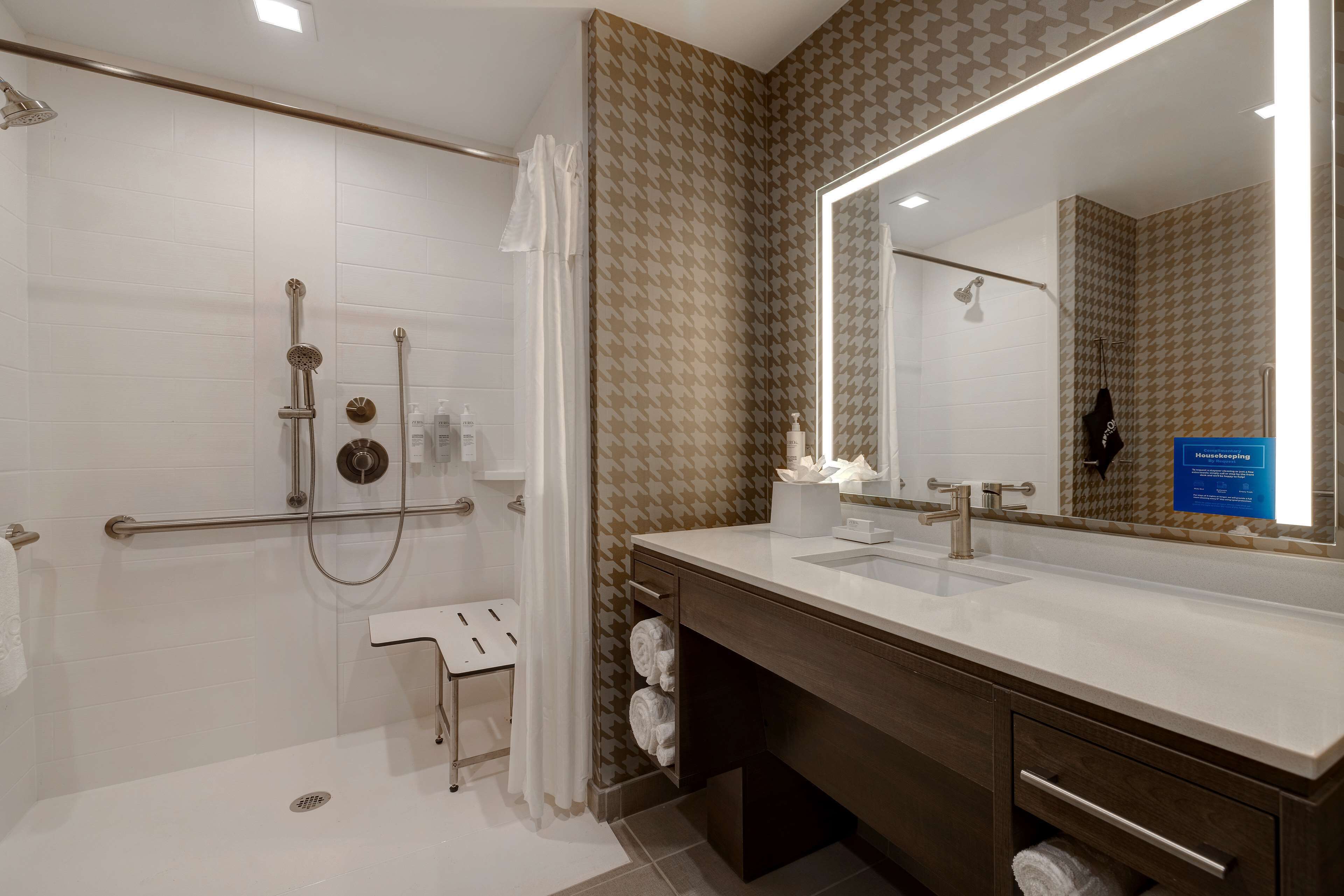 Un bagno moderno con doccia, un mobile vanitario con uno specchio grande e un porta asciugamani.