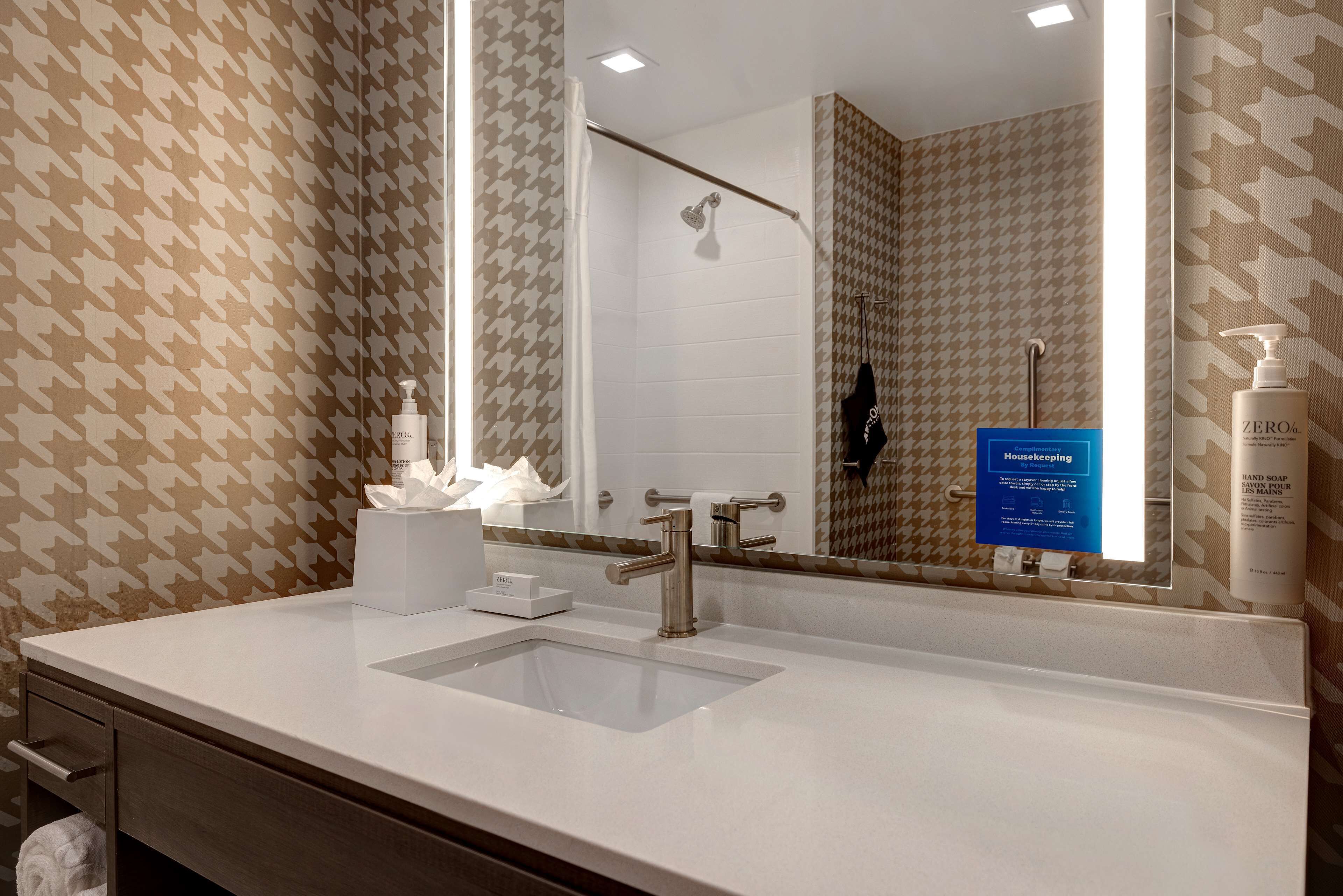 A bathroom with a white sink, a mirror, and a shower area.