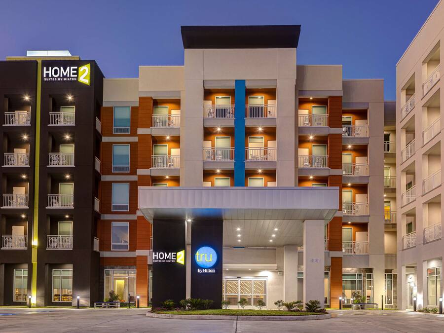Un hôtel moderne doté de nombreux balcons, d’une entrée principale et d’une enseigne bien visible indiquant « HOME 2 by Hilton ».