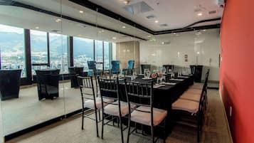 A conference room with a long table, chairs, and a city view through large windows.