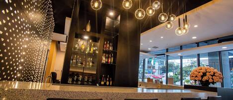 A modern bar area with a granite countertop, bar stools, and a variety of bottles.