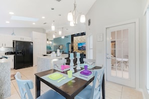 A modern kitchen with a black refrigerator, white cabinets, and a dining area with a table set for four.