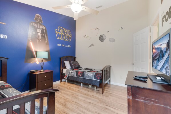 Une chambre à coucher sur le thème de Star Wars, avec un lit, une table de chevet et un ventilateur de plafond.
