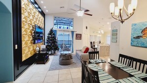 Ein modernes Wohnzimmer mit Essbereich, einem Weihnachtsbaum und einem großen Gemälde einer Schildkröte.