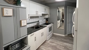 A modern kitchen with white cabinetry, a built-in oven, and a stainless steel sink.