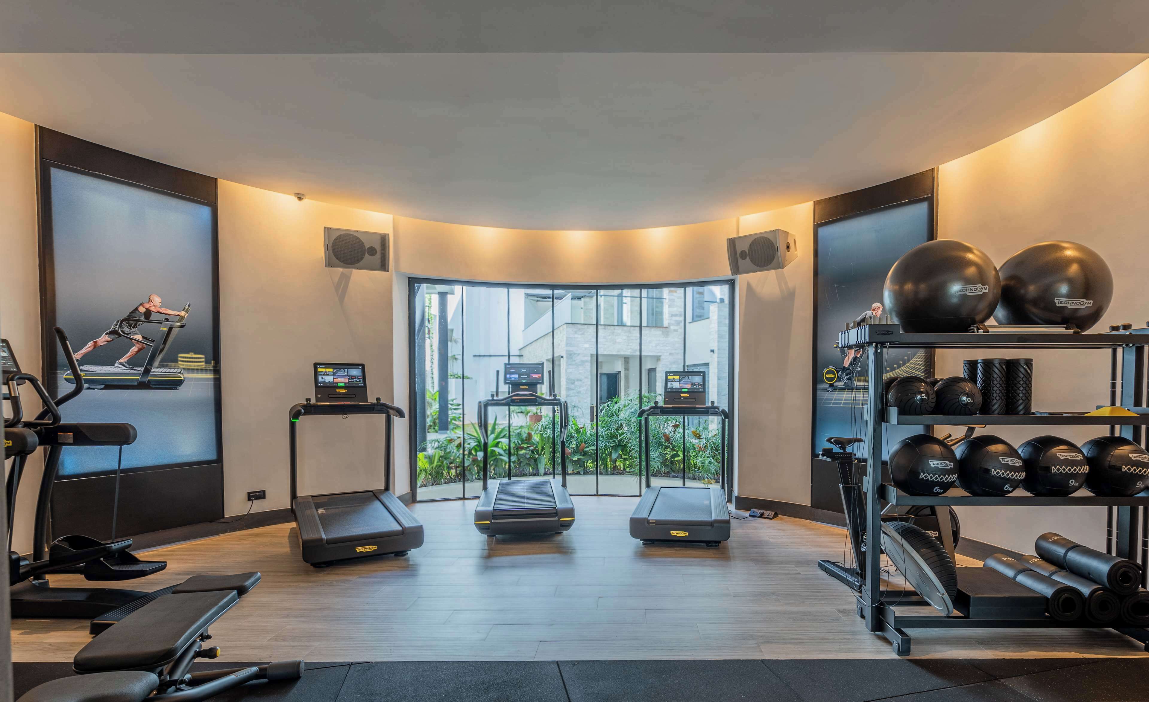 Une salle de sport moderne équipée de tapis de course, d’un vélo d’appartement et de matériel de musculation.
