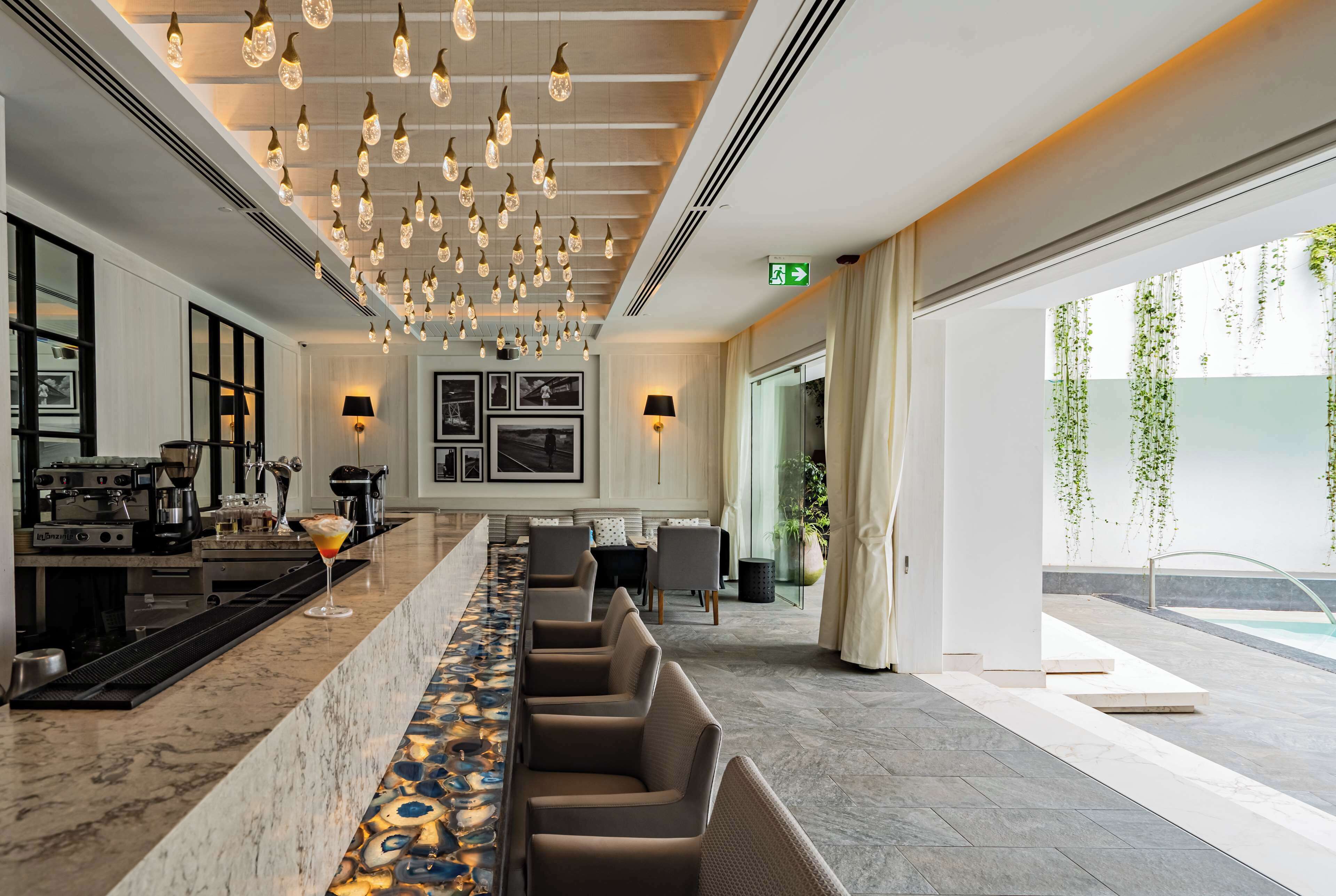 Een moderne bar met een lange toonbank, barstoelen en hangende lampen.