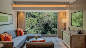 A modern living room with a sofa, coffee table, and a view of a forest through large windows. - Kwetu Nairobi, Curio Collection By Hilton (Nairobi)