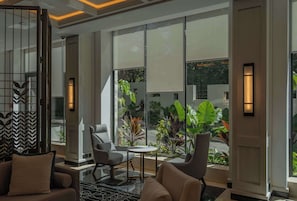 A modern lobby with a seating area, large windows, and indoor plants.