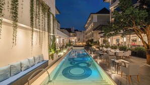 A pool area with a seating bench and tables, surrounded by buildings with outdoor lighting. - Kwetu Nairobi, Curio Collection By Hilton (Nairobi)