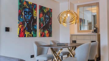 A modern dining area with a table, chairs, and two colorful paintings on the wall.