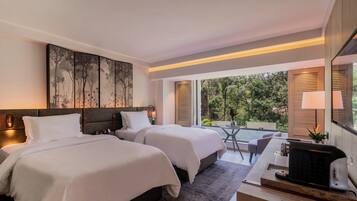 A modern hotel room with two beds, a desk, and a view of the outdoors.